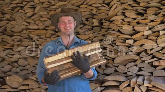 一个男人戴着牛仔帽在仓库里拿着一堆木柴的画像视频的预览图