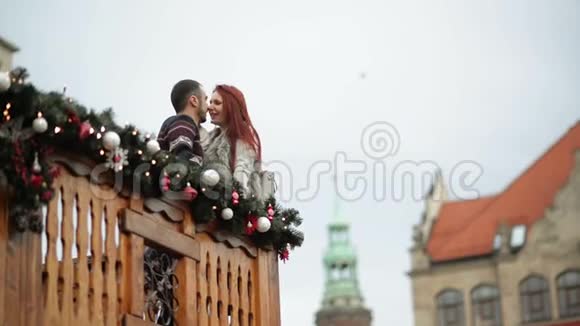 一对恋人在拥抱自己圣诞节期间他们站在木制阳台上新年快乐视频的预览图