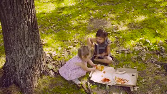 两个女孩在公园里吃披萨视频的预览图