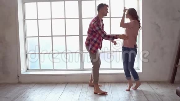 年轻夫妇在家一起情人节的概念就在窗边跳舞嬉戏视频的预览图