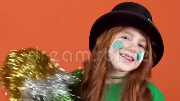 女孩红发庆祝圣帕特里克日橙色背景跳舞与pompom视频的预览图