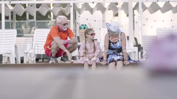 幸福成熟的夫妇和小孙女在豪华游泳池的边缘祖母祖父和孙子视频的预览图