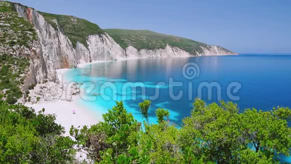 希腊基法隆尼亚有岩石海岸线的蓝色泻湖平静清澈的蓝绿色绿松石海水白沙滩视频的预览图