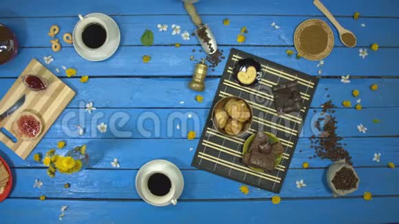 蓝色木桌上的咖啡和甜点上景慢动作视频的预览图