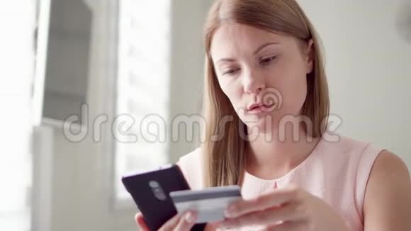 年轻漂亮的女人坐在家里用信用卡在线购物网上消费主义视频的预览图