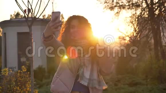 白种人卷发妇女在秋季自然背景下使用智能手机制作自拍照片的肖像视频的预览图