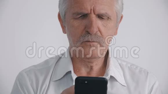 戴胡子的老人在白色背景下使用智能手机的肖像视频的预览图