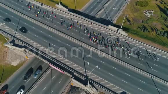 空中无人机镜头跟随马拉松跑小组在公路路口关闭视频的预览图