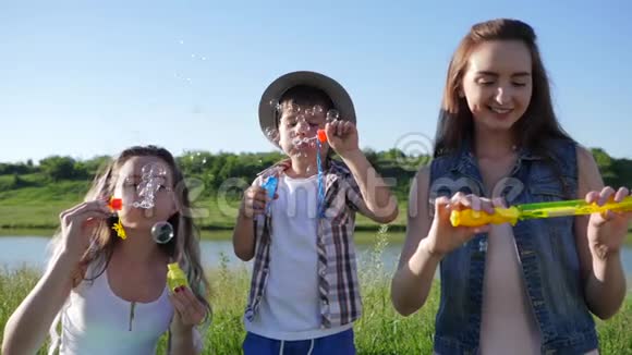 欢乐的童年欢乐的孩子们在背景天空的洛夫附近的草坪上用肥皂泡视频的预览图