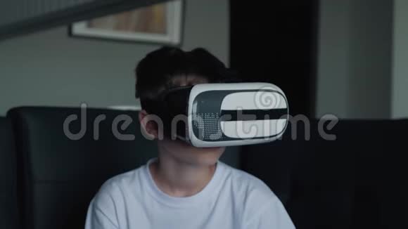 一个快乐的男孩戴着虚拟现实眼镜在家里玩游戏看电影虚拟现实眼镜新技术视频的预览图
