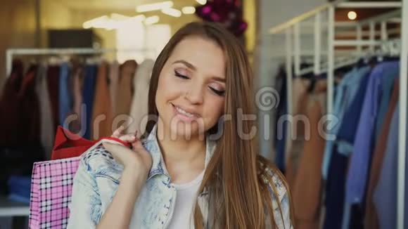 特写照片一个漂亮的年轻女孩站在服装店的纸袋里面带微笑地看着镜头视频的预览图