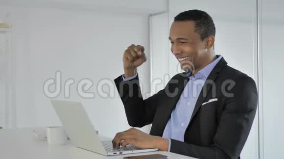 美国黑人商人庆祝成功在笔记本电脑上工作视频的预览图