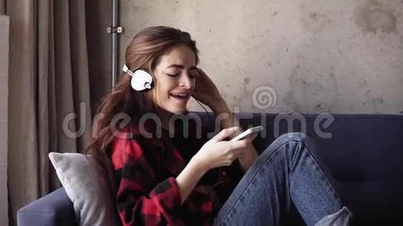 迷人的年轻女孩头上戴着耳机喜欢听她最喜欢的音乐视频的预览图
