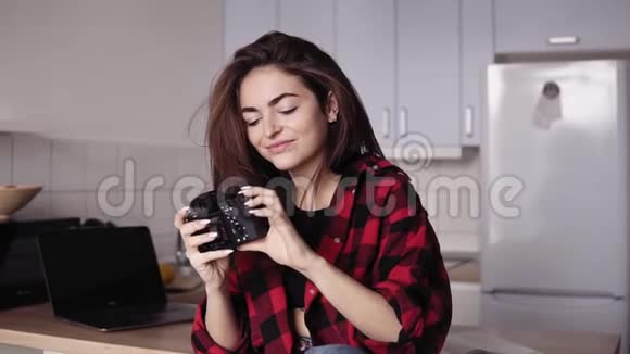 年轻迷人的黑发女孩正在做滑稽的脸试图用专业的照片相机自拍视频的预览图