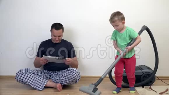 男人看报纸而孩子用吸尘器打扫房子视频的预览图