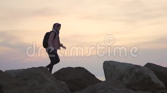 年轻的女旅行者沿着山脊走陡峭的山日落时可以看到美丽的海景视频的预览图