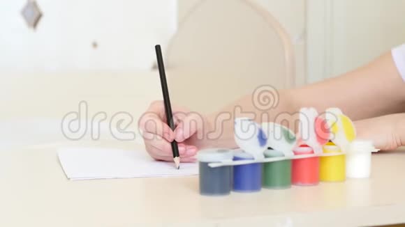 妈妈在一张白纸上画水彩画给坐在桌子旁的孩子女孩画了一幅画特写镜头视频的预览图