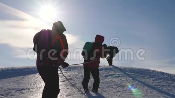 三个登山队员在雪山上爬绳旅游者一起工作集体摇身一变克服困难视频的预览图