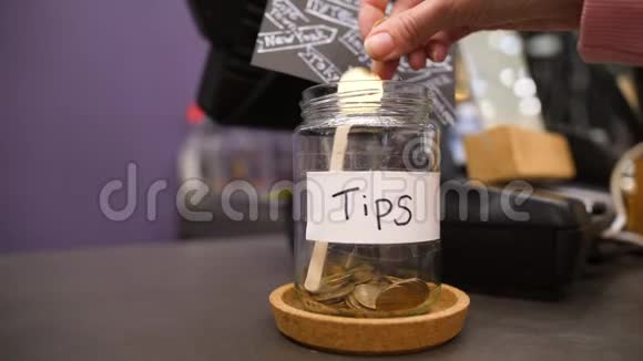 女顾客手把钱币放进咖啡店的小费罐里4K视频的预览图