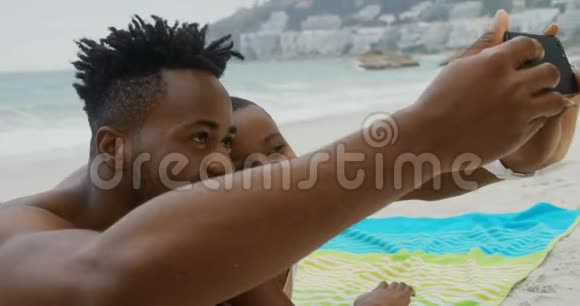 非裔美国人夫妇在海滩上用手机自拍的正面景色视频的预览图