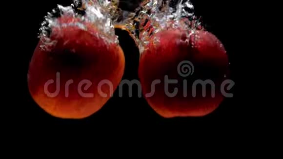 2两个红苹果落在黑底透明的水里视频的预览图