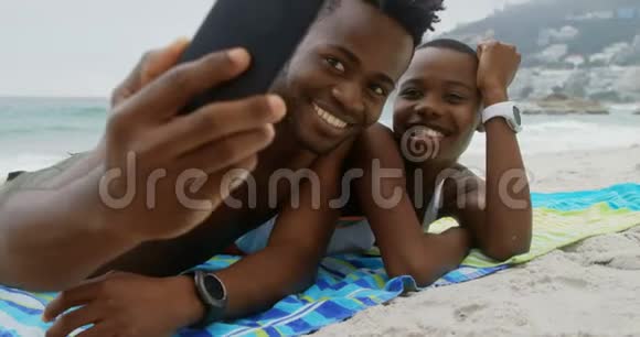 非裔美国人夫妇在海滩上用手机自拍的正面景色视频的预览图