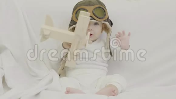 带飞行员帽玩木飞机玩具的搞笑宝宝快乐的孩子笑脸概念性视频的预览图