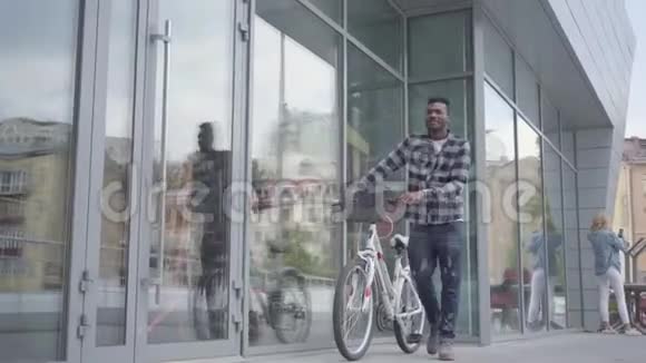 肖像自信英俊的非裔美国人站在城市建筑的背景下骑自行车这就是视频的预览图