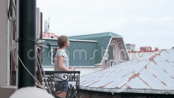 早上的年轻女子在阳台上喝茶或咖啡视频的预览图