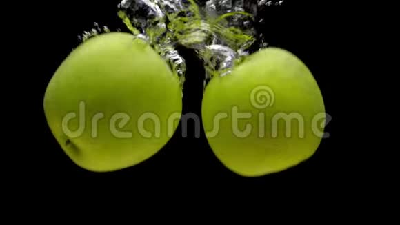 两个黄色的苹果落在黑色背景的透明水中视频的预览图