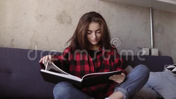 年轻迷人的黑发女孩说了些什么边看书边笑视频的预览图