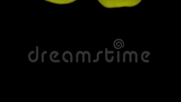 两个黄色的苹果落在黑色背景的透明水中视频的预览图