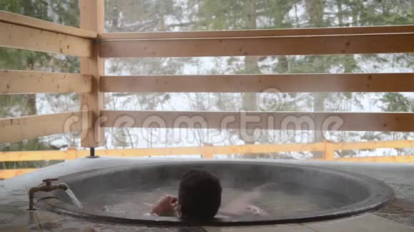 一个男人正在用矿泉水在铸铁缸里洗澡用冷水关掉水龙头视频的预览图