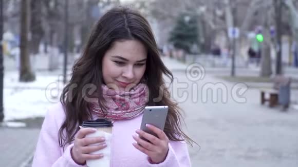 聊天女孩正坐在网上手里拿着塑料杯的手机视频的预览图