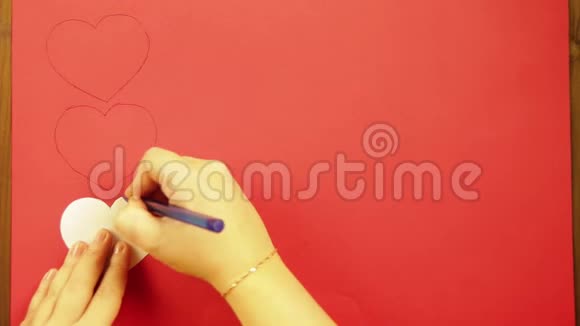 这个女孩画着一颗红色的纸板心特写视频的预览图