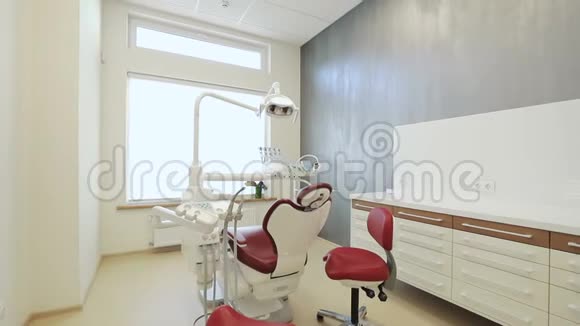 奢华的极简牙科诊所内部配有红色椅子和工具玻璃墙上的牙科灯视频的预览图