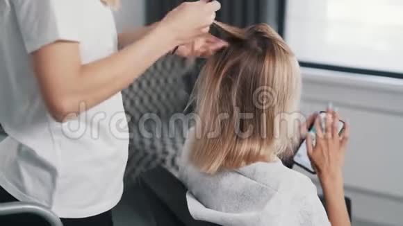 把理发师的手贴在年轻女性的头发上视频的预览图