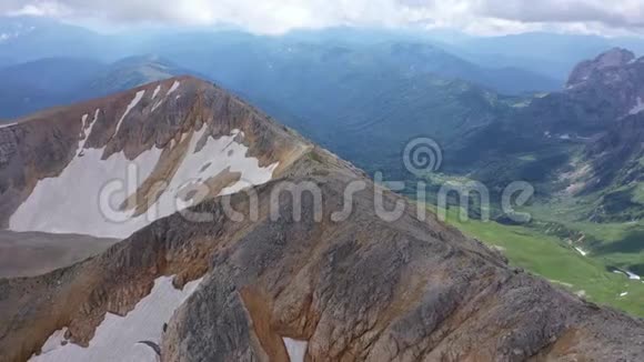 在岩石悬崖冰川和雪峰上拍摄的山脊的空中拍摄令人惊叹的山景视频的预览图