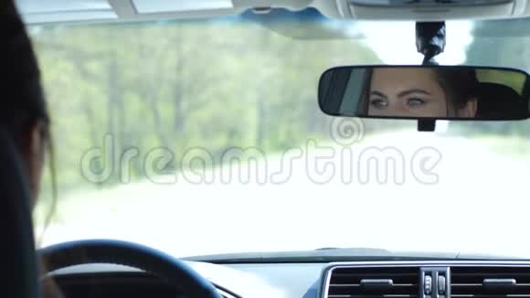 女司机在车后照镜子在旅行中骑在路上视频的预览图