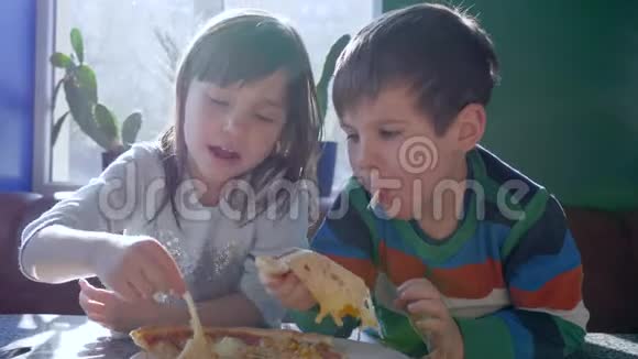 快餐孩子们在午餐时吃美味的披萨坐在桌子上靠在窗户上视频的预览图
