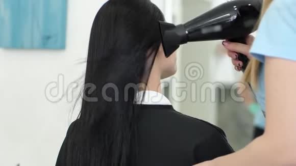 美容工作室理发师手里拿着吹风机在客户头上吹暖气视频的预览图