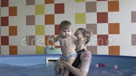 一个小孩在游泳池里的教练手里视频的预览图