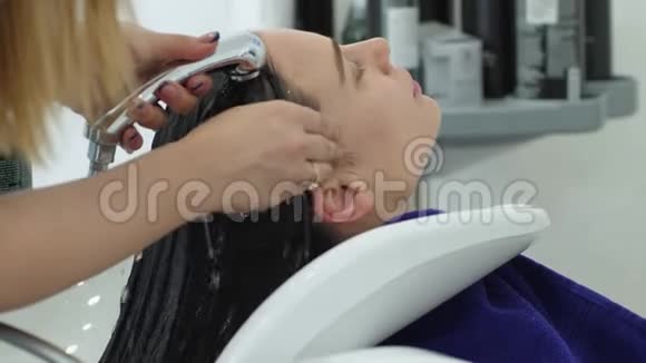 女性卫生美容师在美容院洗手客户头发视频的预览图