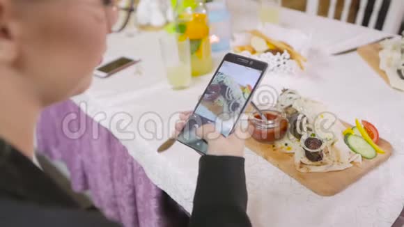 女性的双手正在餐厅的智能手机上吃一道开胃的肉菜视频的预览图