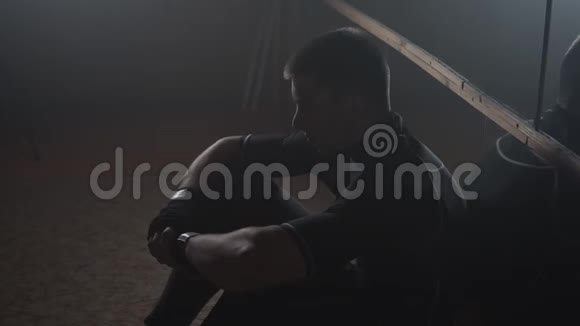 战士在镜子前锻炼时休息年轻人独自坐在健身房里视频的预览图