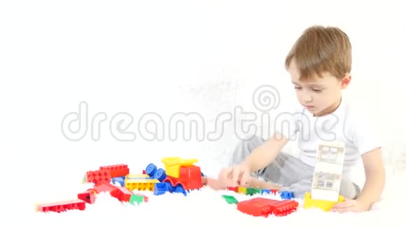 快乐的孩子坐在白色的背景上在彩色的积木里玩耍一个孩子在沙发上玩运动摄像机视频的预览图