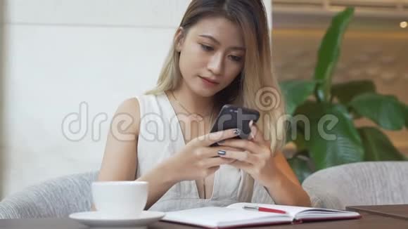女人在智能手机上使用应用程序喝咖啡微笑在手机上发短信视频的预览图