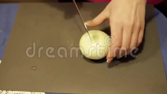 家庭主妇把洋葱切成两半厨师用洋葱做蔬菜沙拉把洋葱加到盘子里视频的预览图