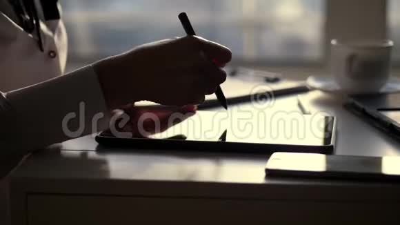 女商人的黑色轮廓手的特写她在平板电脑里写东西接下来是桌上的笔记本电脑模糊的视频的预览图
