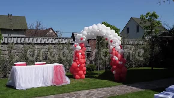 婚礼拱门由红白气球制成婚礼仪式绿色草坪视频的预览图